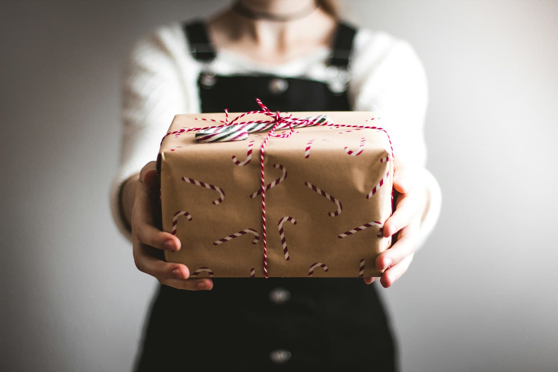 Someone offering a thoughtfully wrapped Christmas gift